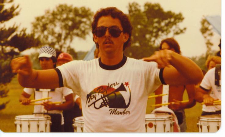 1983 Sky Ryders Drum Corps Major, Victor, wearing a member's T-shirt.